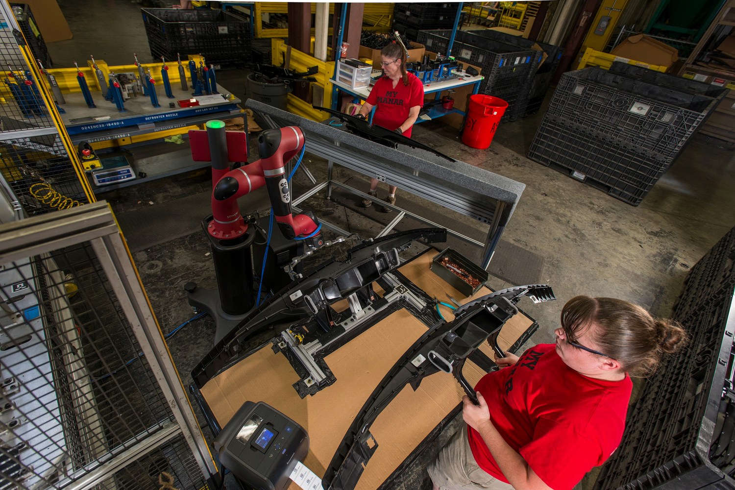 Collaborative robot operating within a guarded production workstation while factory personnel manage material flow